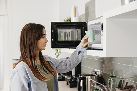 Mujer metiendo un vaso en un microondas