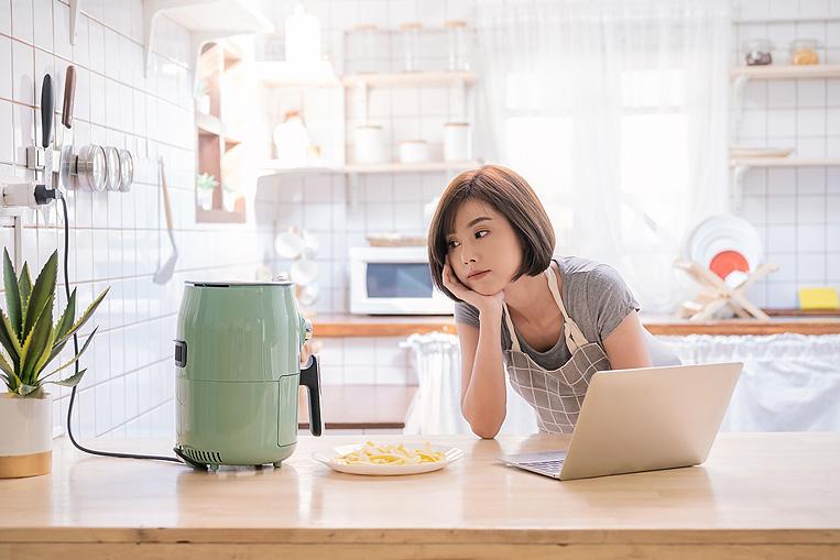 Mujer mirando l freidora de aire en la cocina