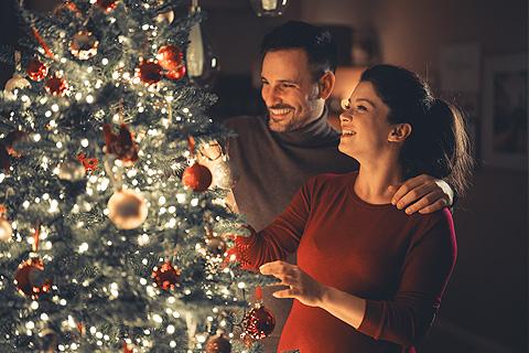 Pareja poniendo las luces del árbol de Navidad