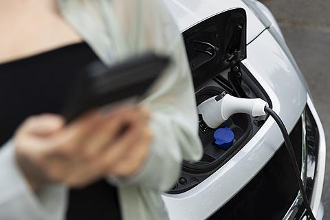 mujer cargando la batería de su coche eléctrico