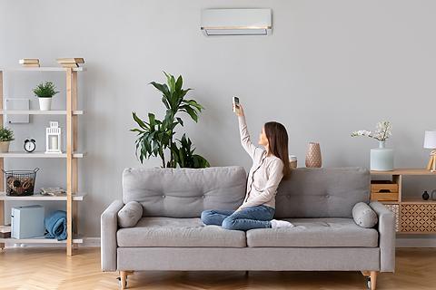 Mujer encendiendo el aire acondicionado para que salga calor